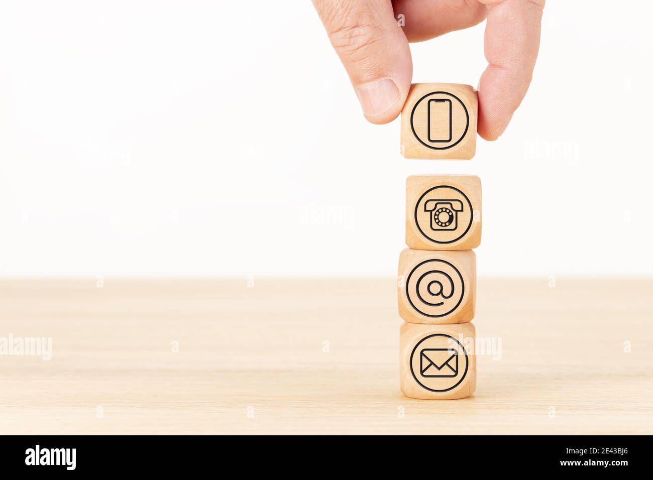 Contact us background. Website page. Hand holding a wooden block and blocks stacked with contact icons. Copy space. White background Stock Photo