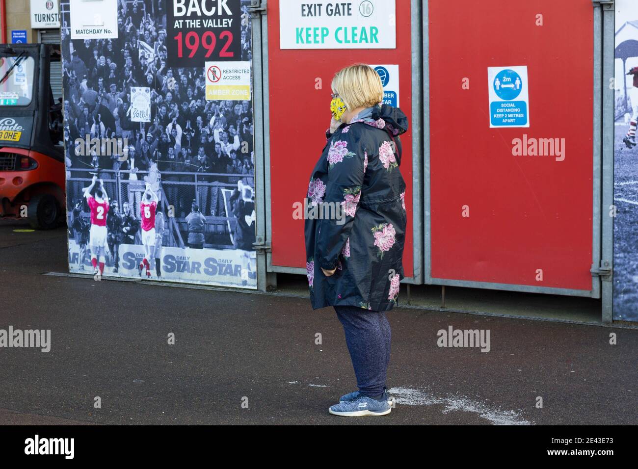 Face mask wearing women waiting in queue for covid-19 vaccine, in the Valley stadium, Charlton, London, England Stock Photo