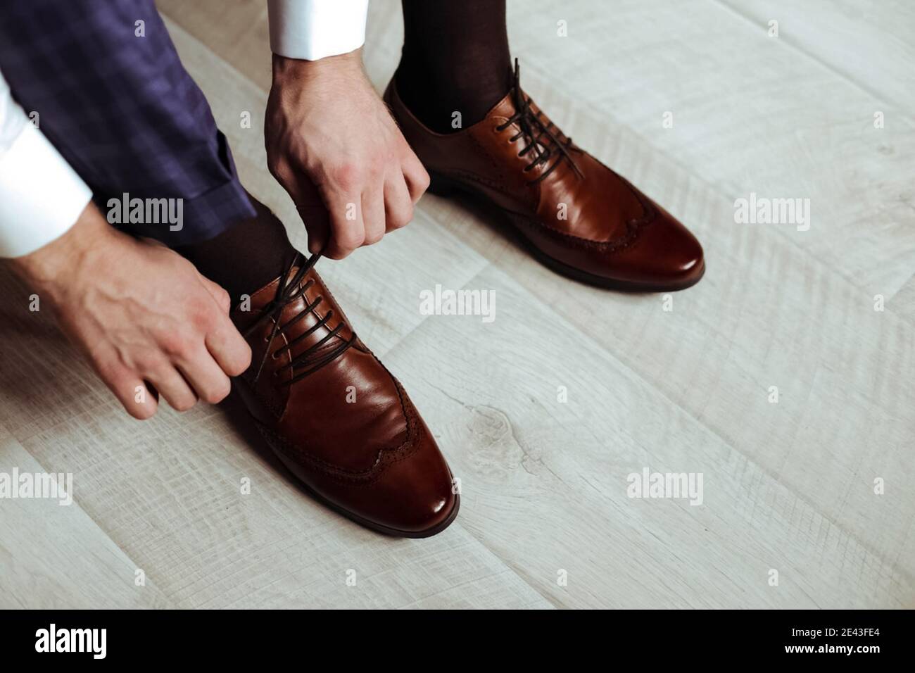 A man ties his shoelaces. Brown shoes Stock Photo Alamy