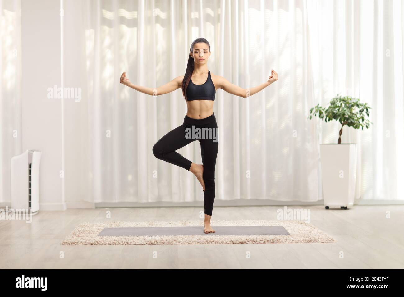 Full length portrait of a young woman practicing yoga at home Stock Photo