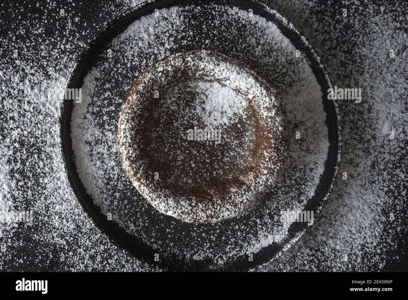 Top view of sweet chocolate coulant placed on black background with sugar powder Stock Photo
