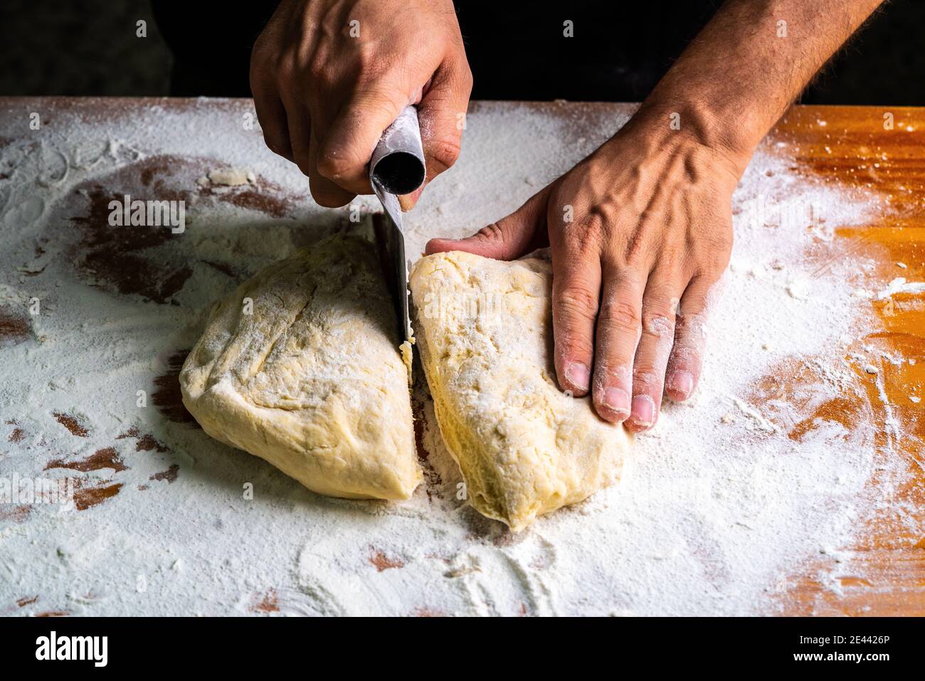 Woman using a dough cutter to divide the naan bread dough into six equal  portions which are flattened and baked. Bakers and pas Stock Photo - Alamy