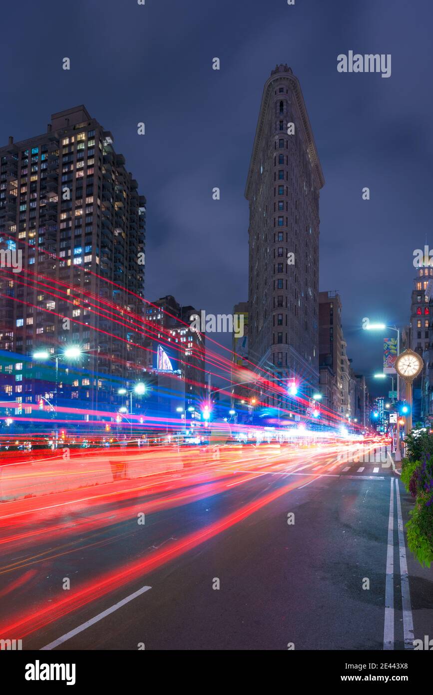 NEW YORK, EEUU - September 21, 2018 - Long exposure of illuminated road with traffic lights and view of landmarked Flatiron Building facade against da Stock Photo