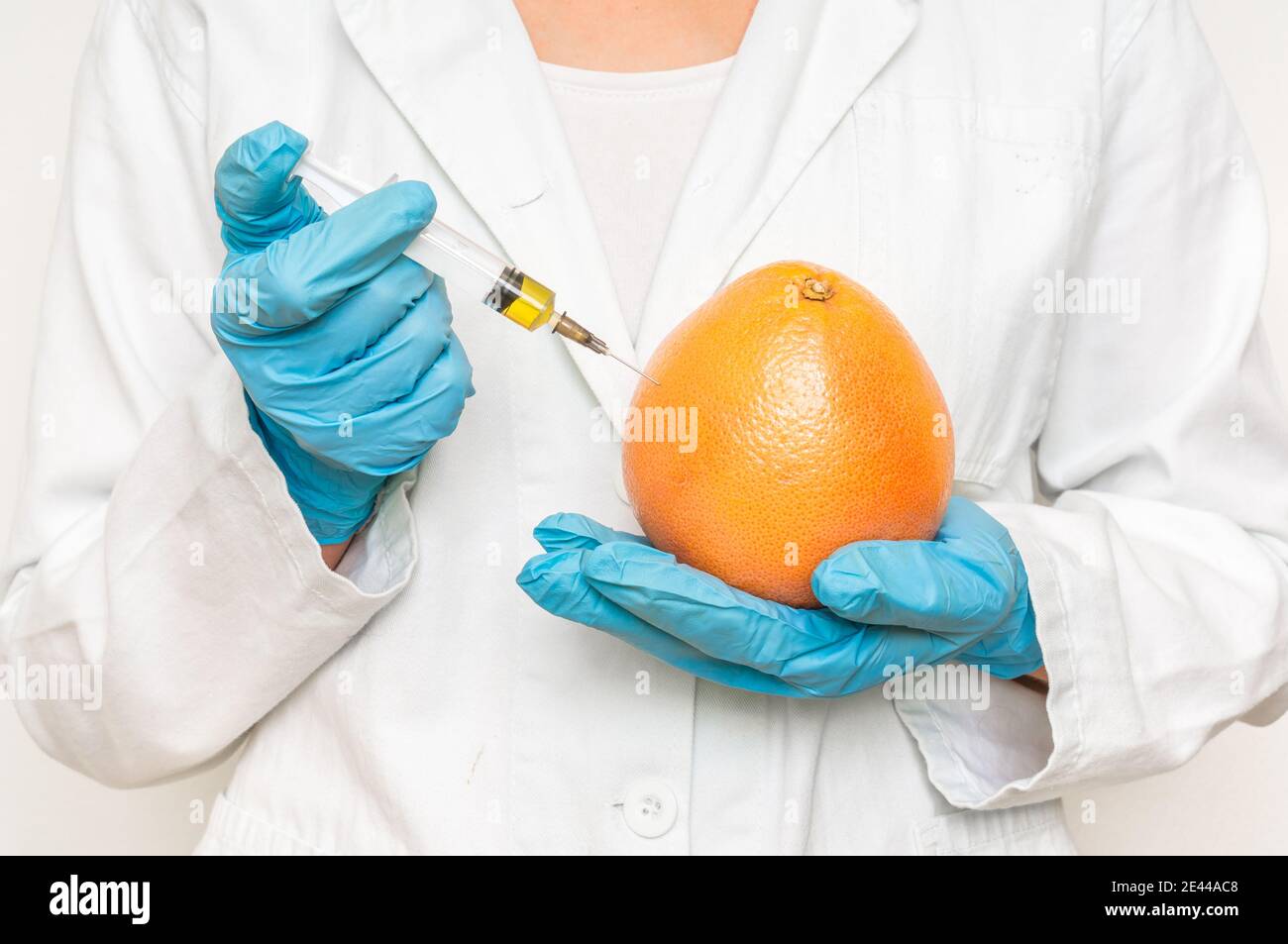 GMO scientist injecting liquid from syringe into grapefruit