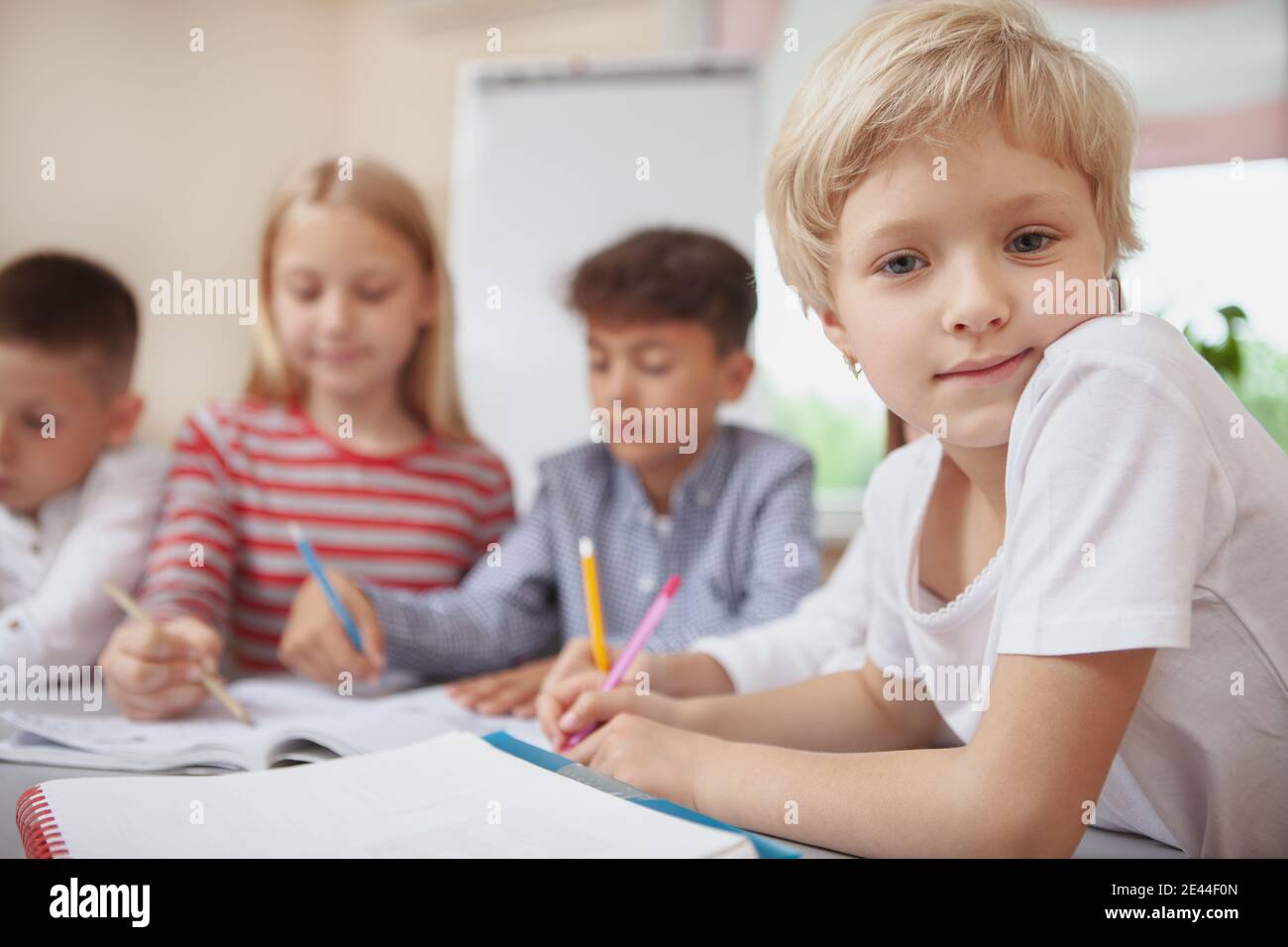 Charming little blond haired girl looking to the camera during art ...