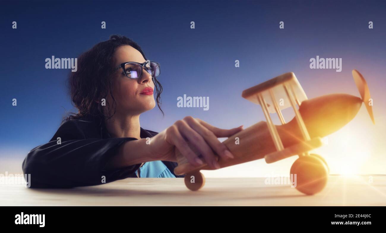 Woman with vintage wooden toy plane dreams of achieving desired goals Stock Photo