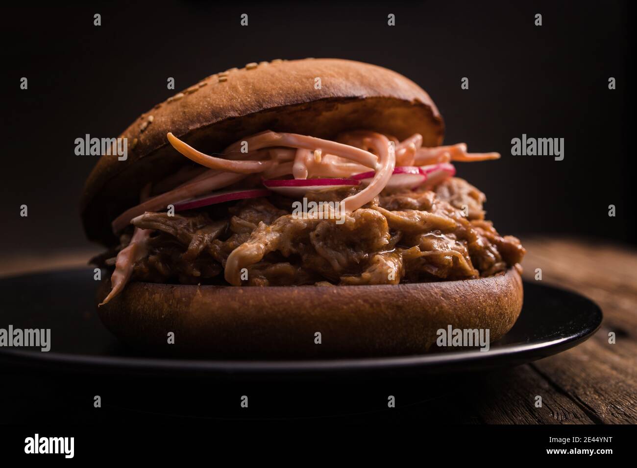 Closeup of yummy hamburger with juicy pulled pork and vegetables in