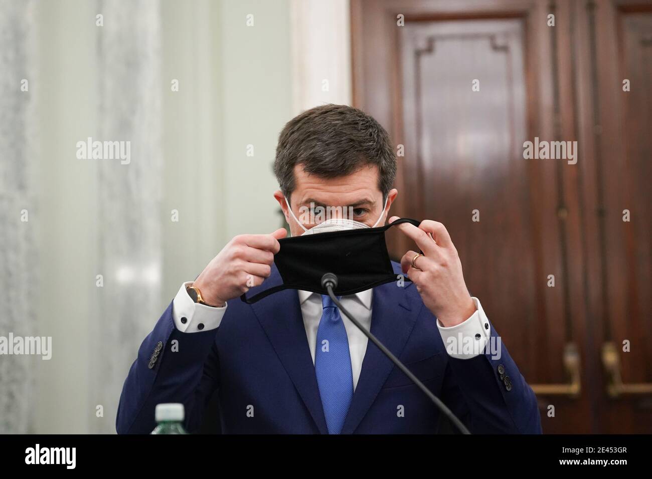 Washington, DC, USA. 21st Jan, 2021. Pete Buttigieg, U.S. secretary of transportation nominee for U.S. President Joe Biden, puts on a protective mask during a Senate Commerce, Science and Transportation Committee confirmation hearing in Washington, DC, U.S., on Thursday, Jan. 21, 2021. Buttigieg, is pledging to carry out the administration's ambitious agenda to rebuild the n sation's infrastructure, calling it a 'generational opportunity' to create new jobs, fight economic inequality and stem climate change. Credit: Stefani Reynolds/Pool via CNP | usage worldwide Credit: dpa/Alamy Live News Stock Photo