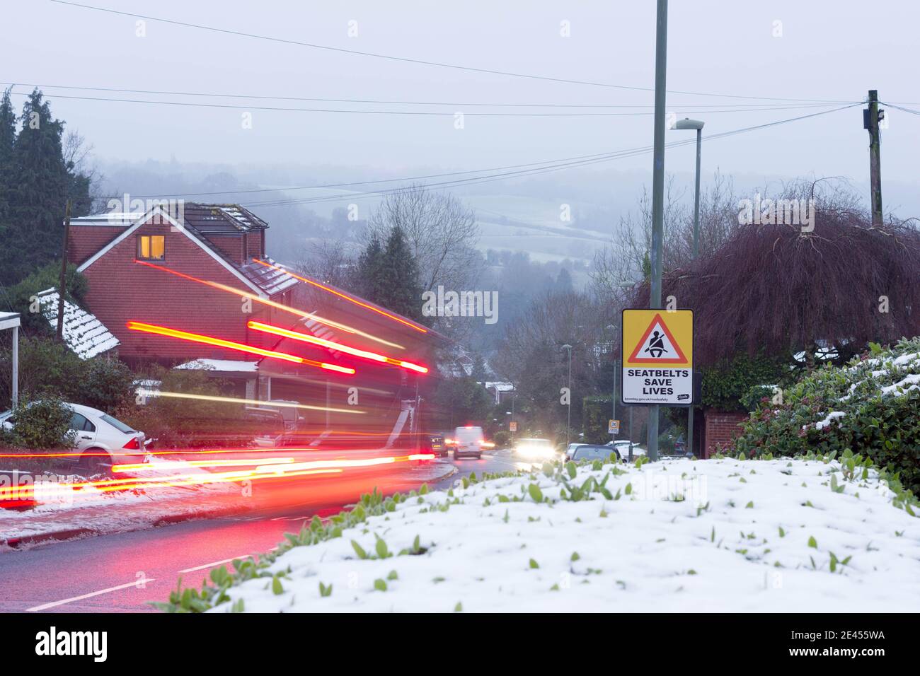 Light trails on snow covered road and hedges, Bromley  London, England UK Stock Photo