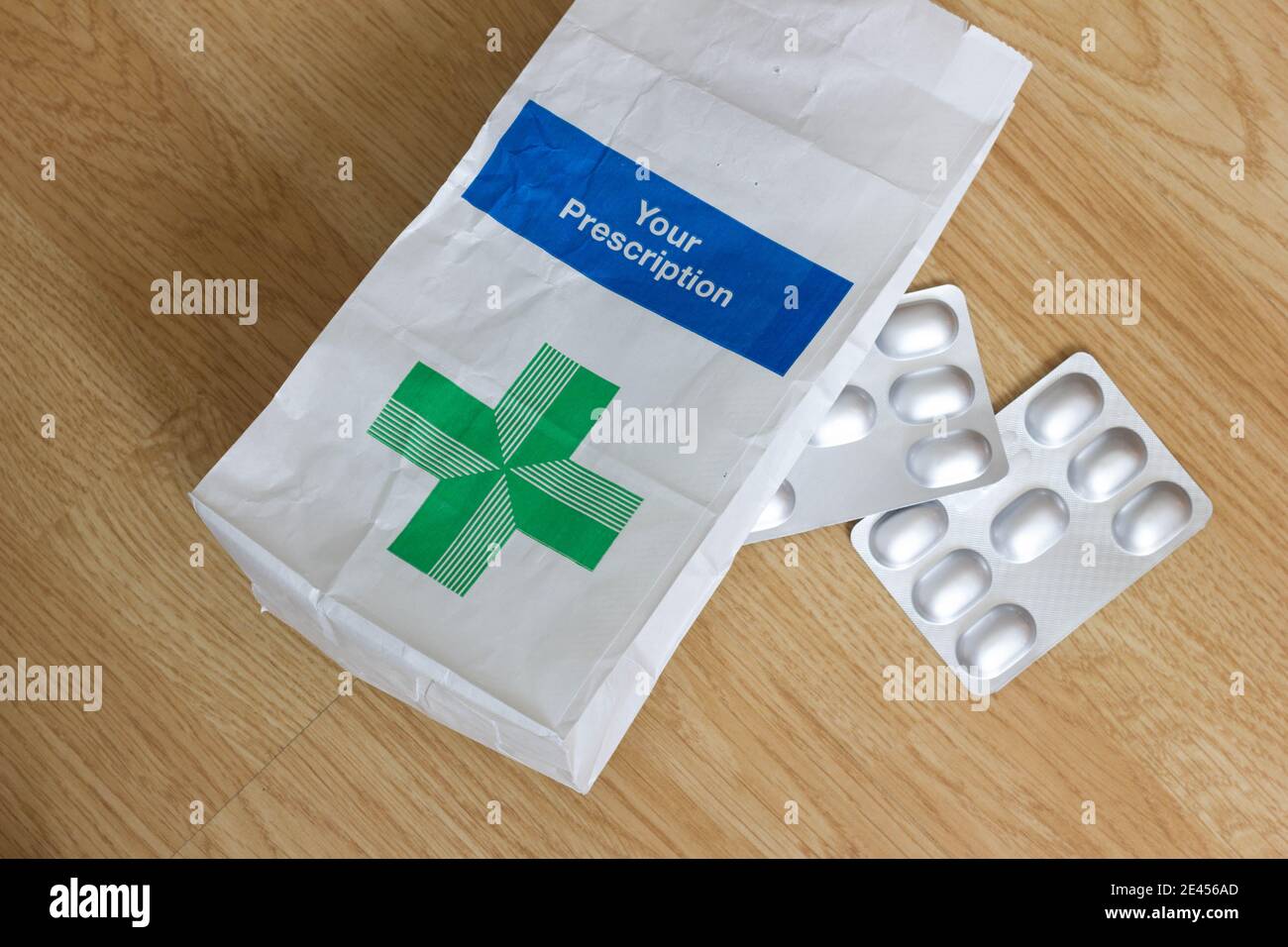 "your Prescription" written on Single NHS prescription paper bag, with a packet of tablets drug on a table top, England Stock Photo
