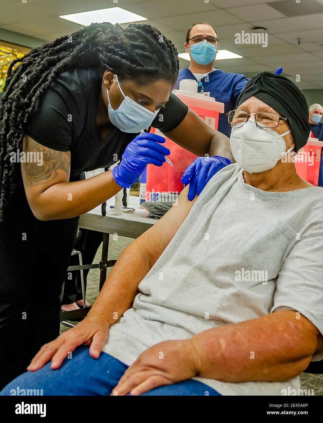 A healthcare worker administers the first dose of the COVID-19 vaccine from Pfizer-BioNTech to a 74-year-old woman in Mobile, Alabama. Stock Photo