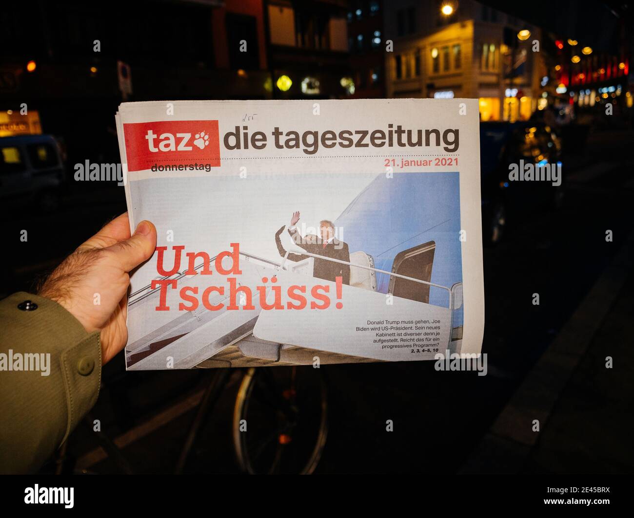 Paris, France - Jan 21, 2021: POV man buying Taz die tageszeitung German newspaper headline words Und Tschuss translated as good bye featuring Donald and Melania Trump leaving the presidency Stock Photo