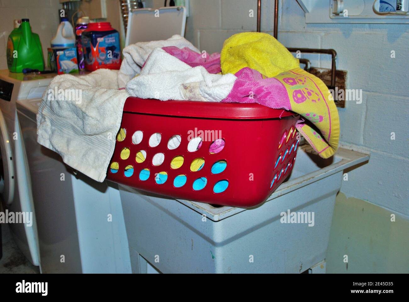 Basket full of dirty towels that need to be washed in a basement
