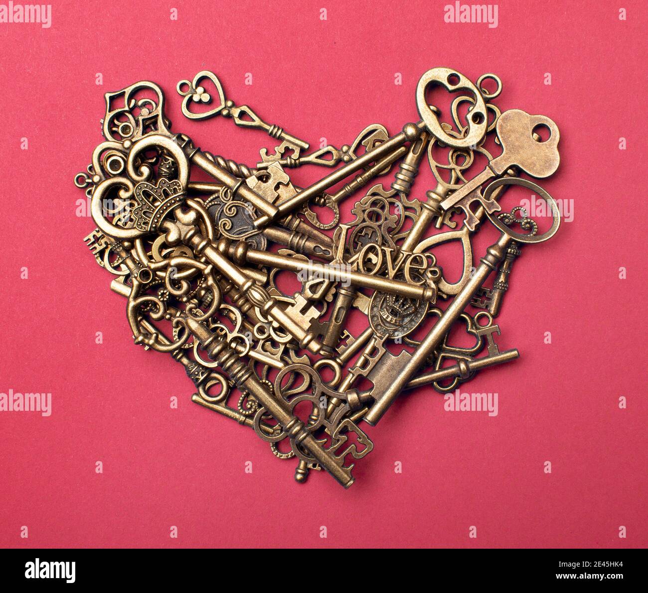 Old, vintage keys in the shape of a heart isolated on pink color bacground Stock Photo