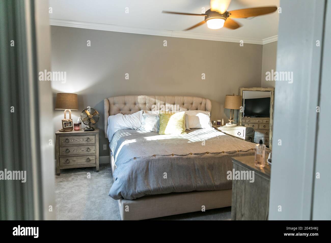 Spacious beige carpeted master bedroom with king sized bed Stock Photo