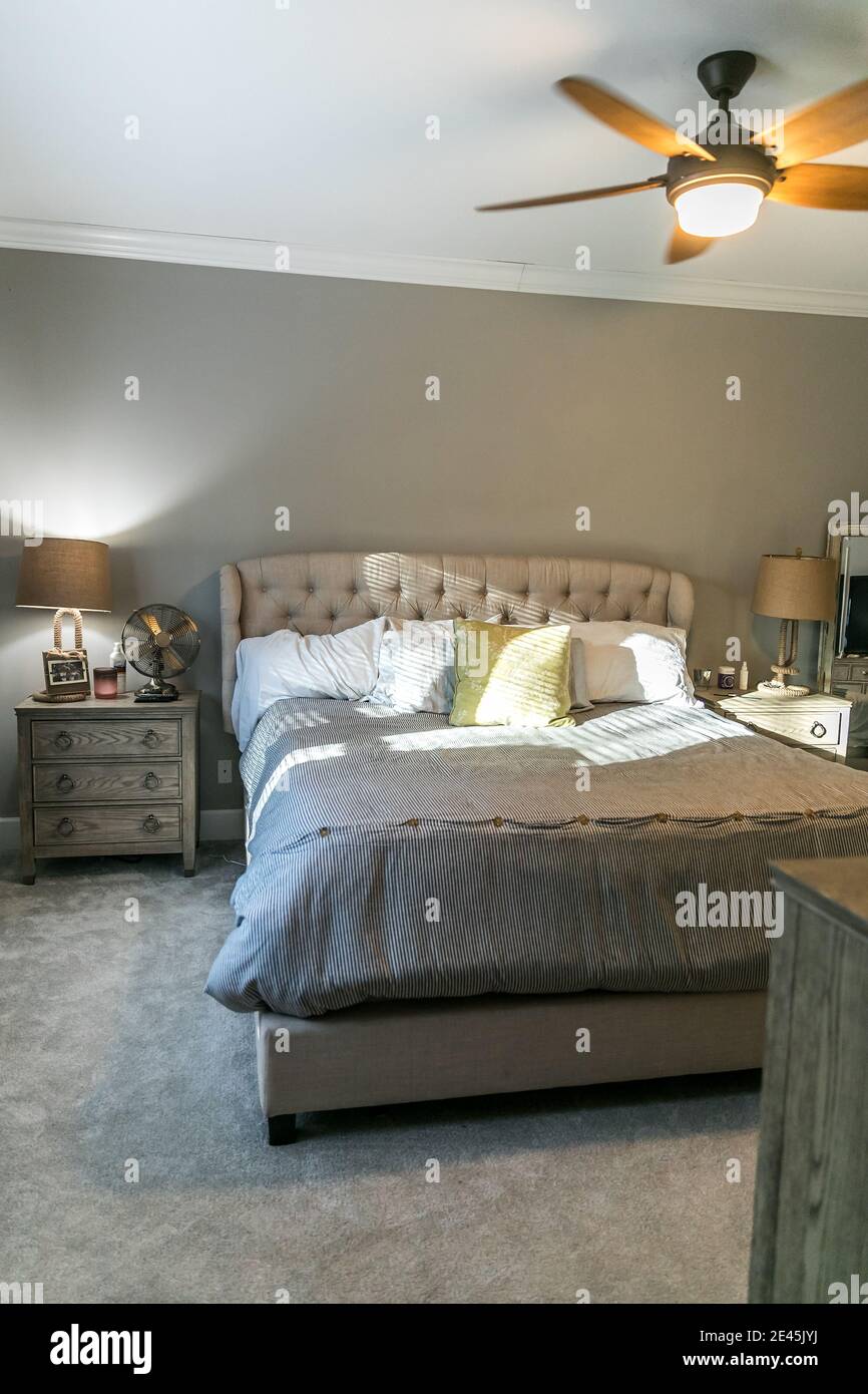Spacious beige carpeted master bedroom with king sized bed Stock Photo