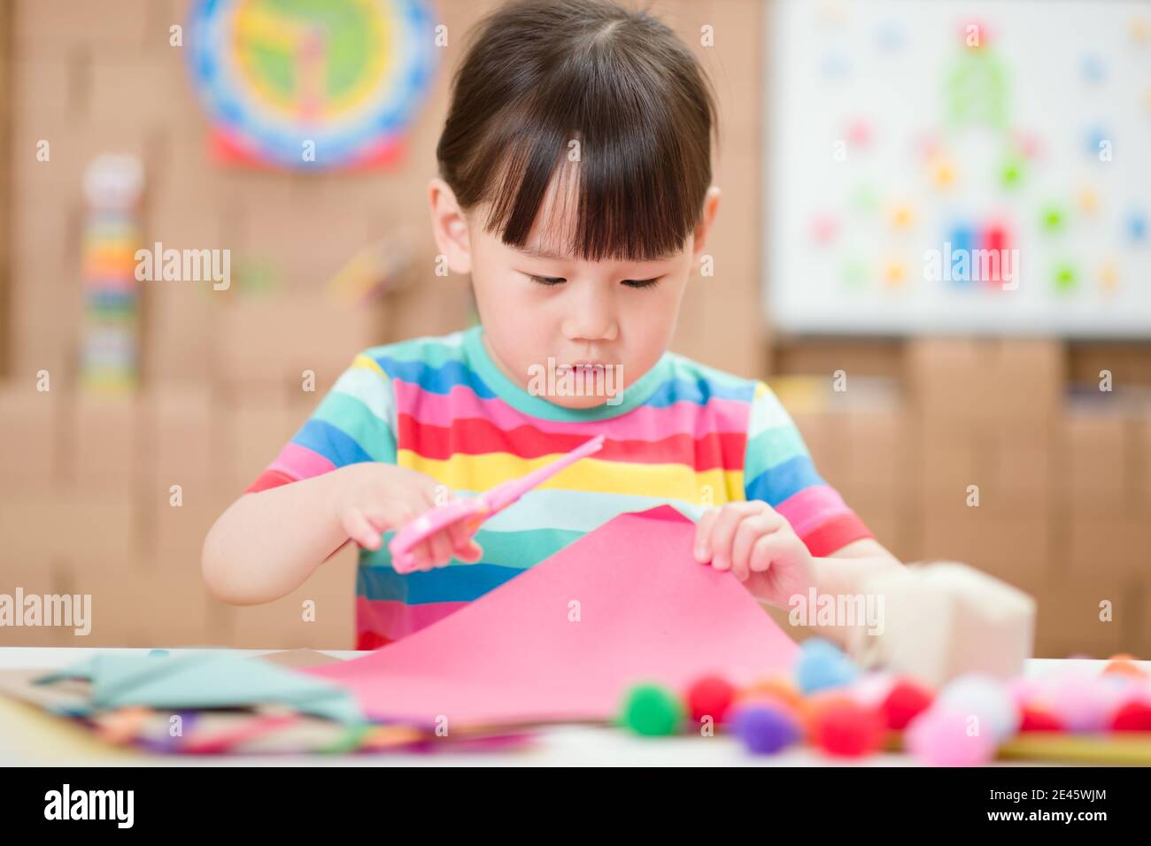 young girl using scissors cutting papper for making craft for