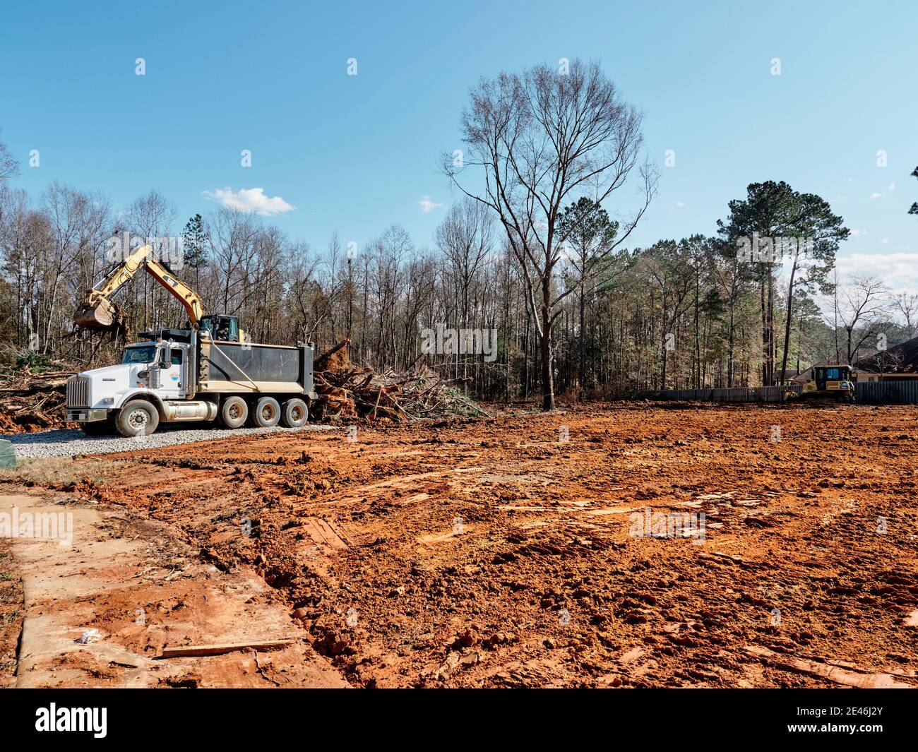 Digger or excavator and dump truck clearing land for new construction building lot in Pike Road Alabama, USA. Stock Photo