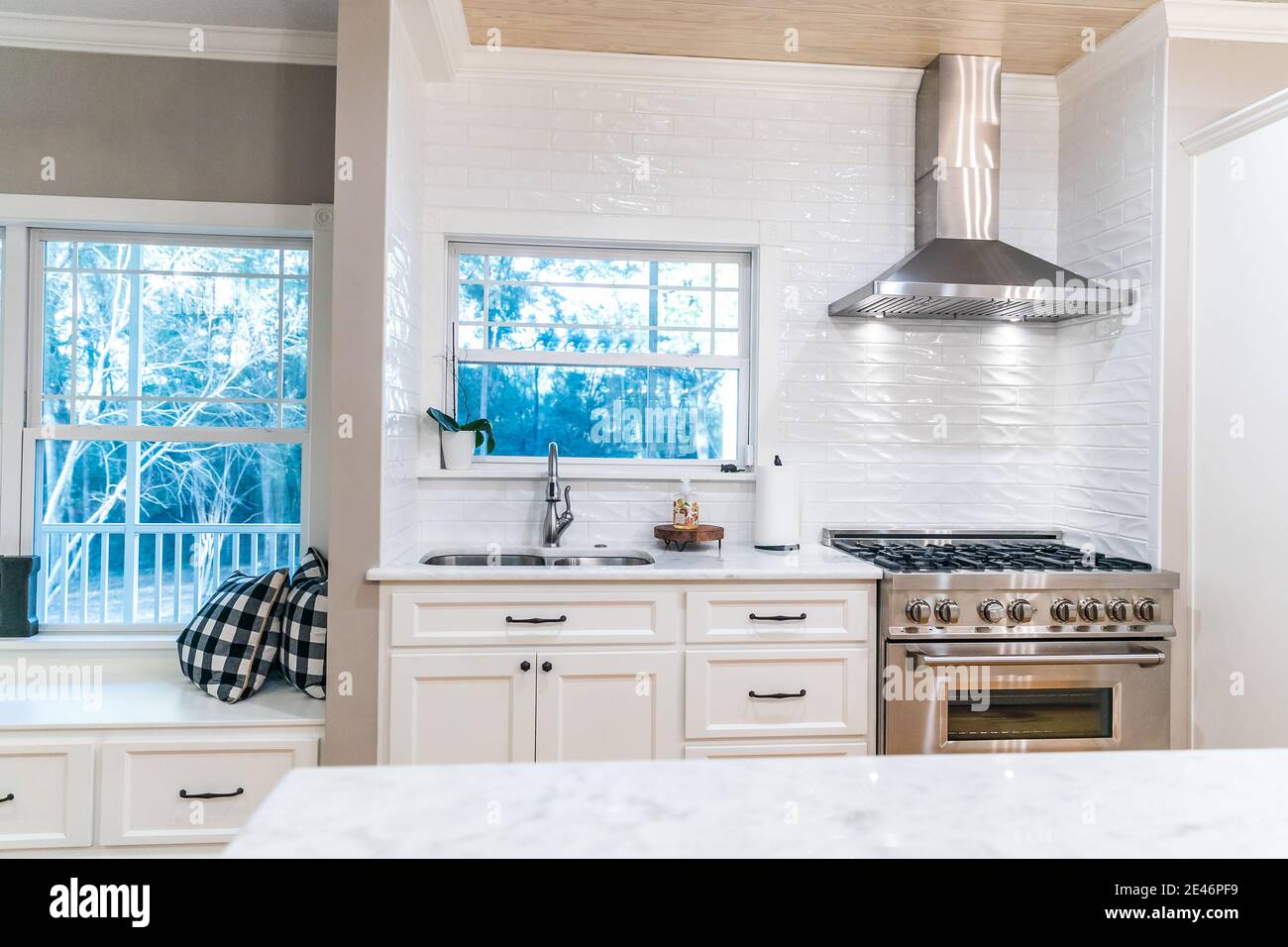 Large renovated white kitchen with textured subway tile, black iron