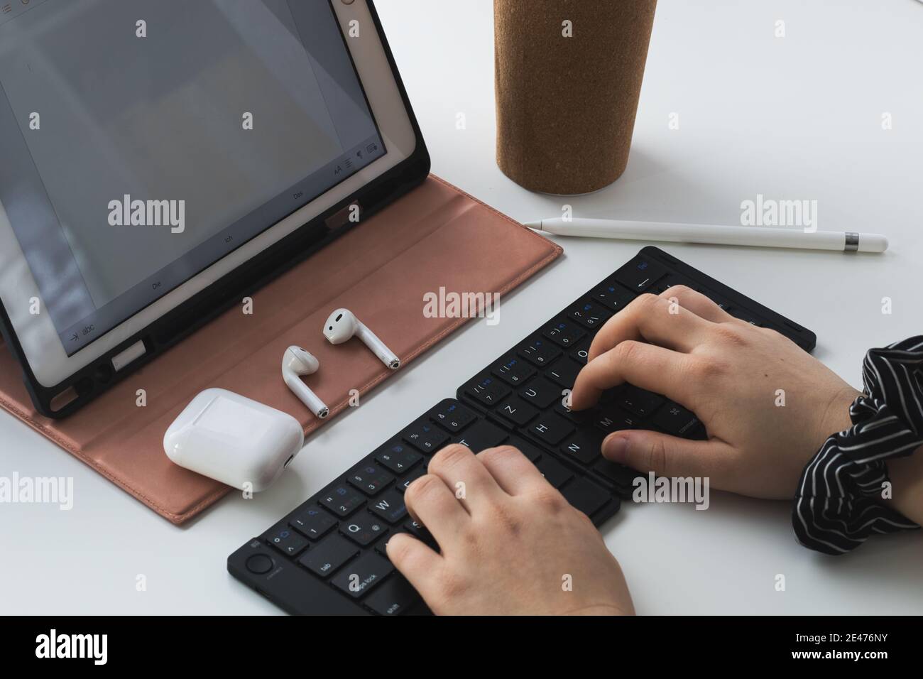 woman typing on a black bluetooth keyboard, working home office at a tablet computer Stock Photo