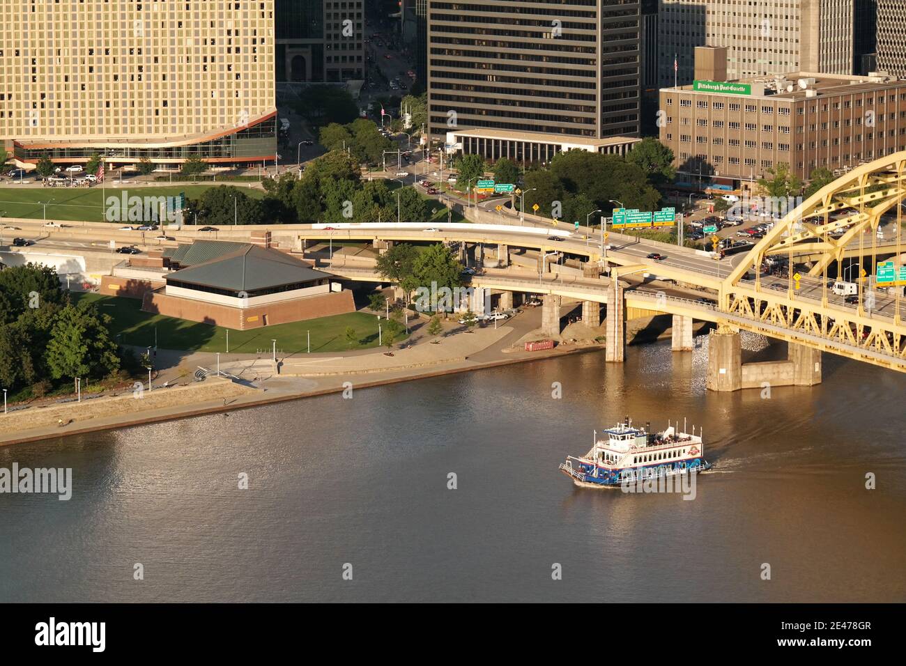 A boat passes by the Fort Pitt Museum and Bridge on the Monongahela River by Point State Park in downtown Pittsburgh, Pennsylvania, USA. Stock Photo