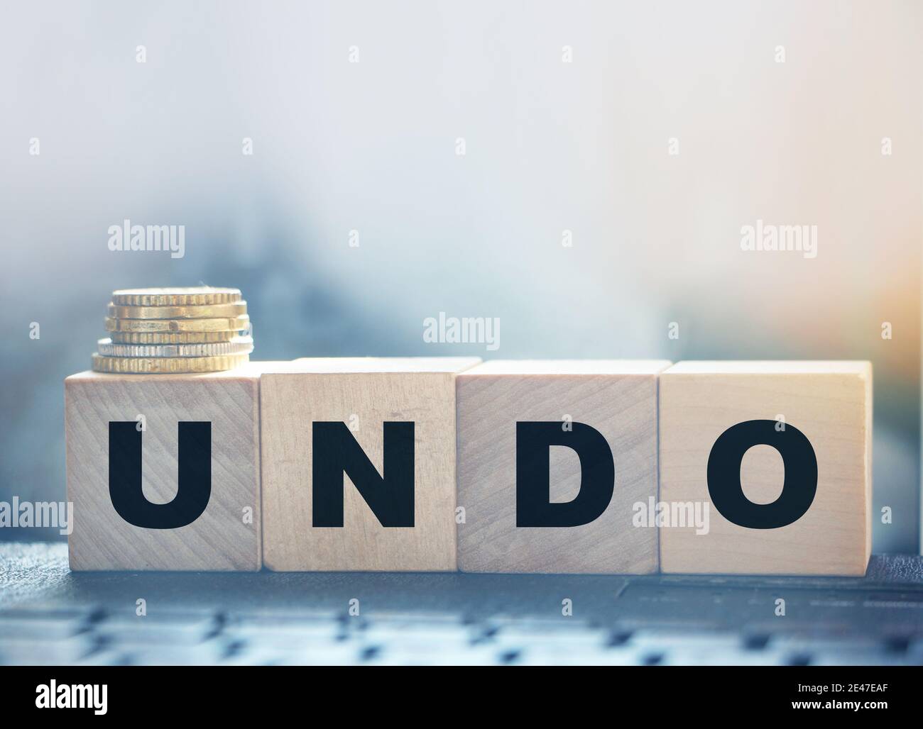 Undo word on wooden cubes with letters, and stack of coins. Technical issue computer program concept. Lifestyle and state of mind concept. Stock Photo