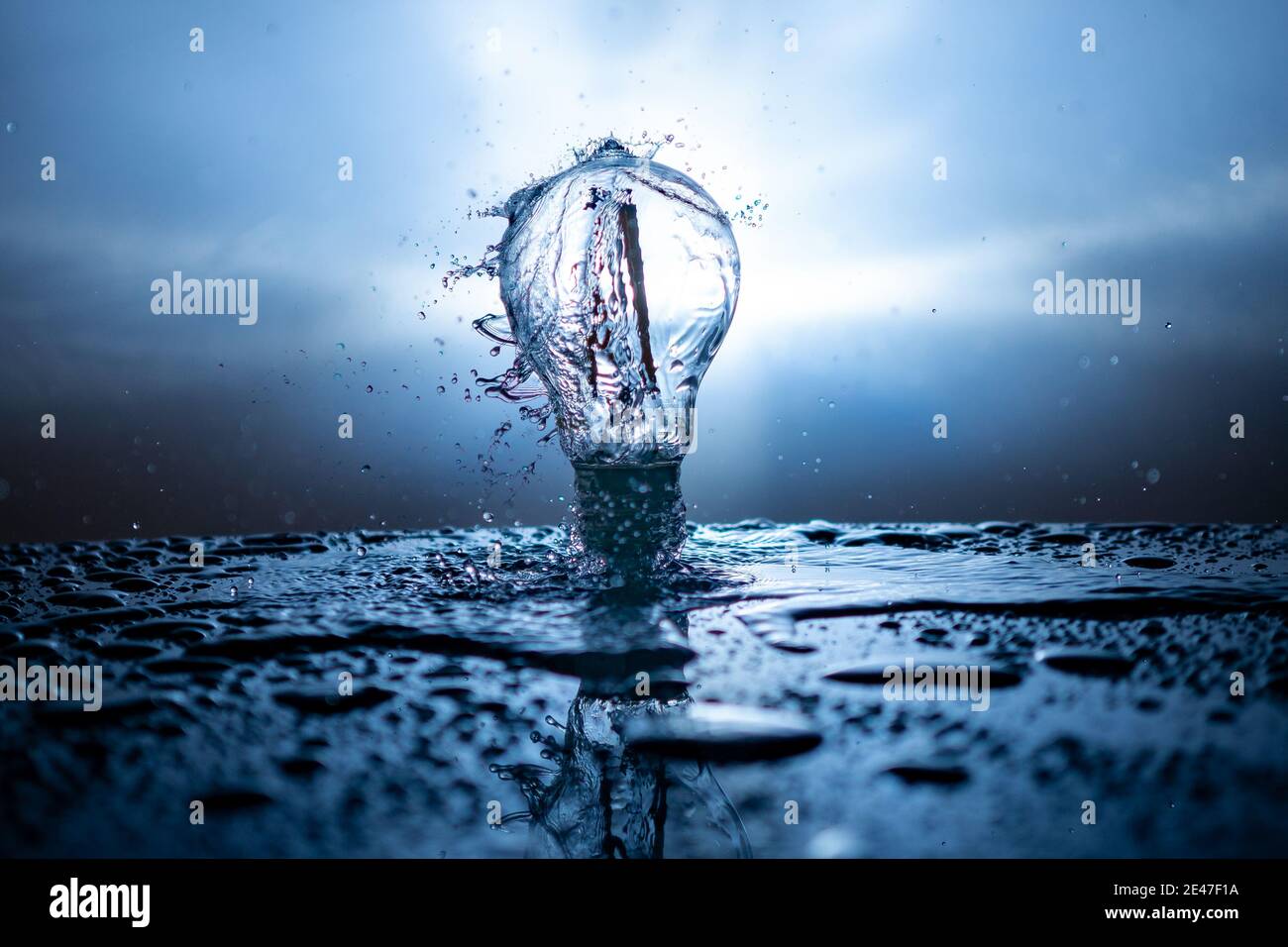 Light bulb with water splashes on a blue background - energy concept ...