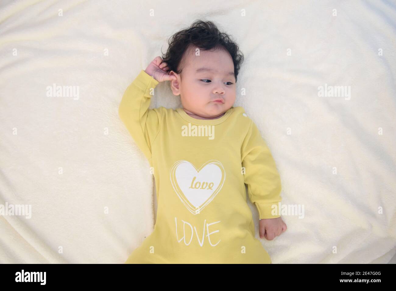 Top view of cute Asian baby girl lying on white bed Stock Photo