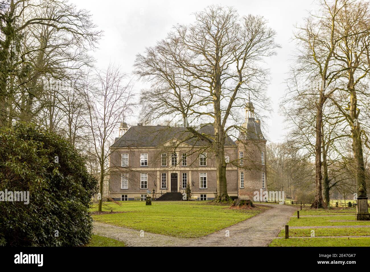 VORDEN, NETHERLANDS - Jan 08, 2021: Arrival yard and entrance of the stately Hackfort castle flanked by winter barren trees Stock Photo
