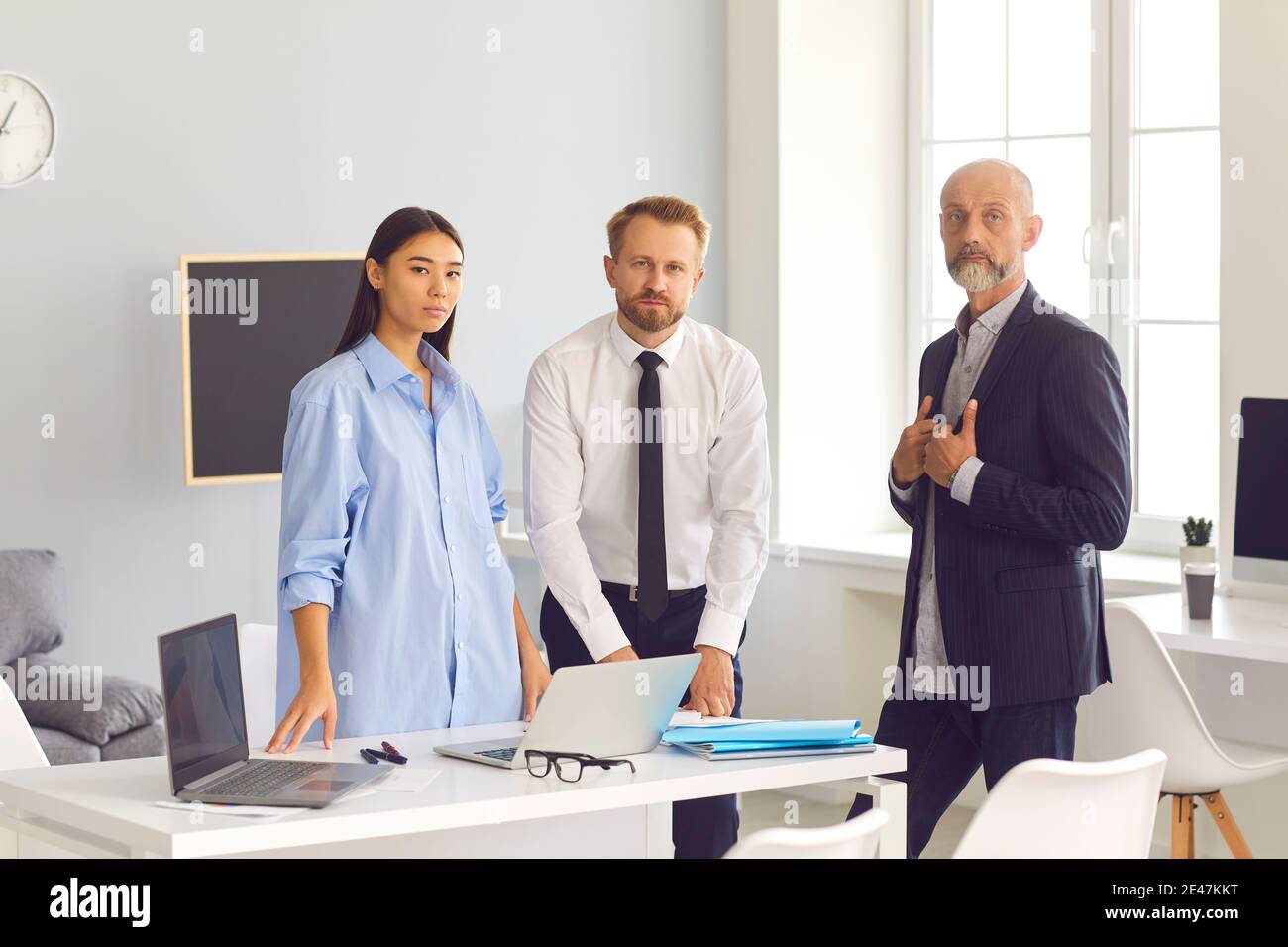 Group of serious diverse employees standing in office of their company looking at camera Stock Photo