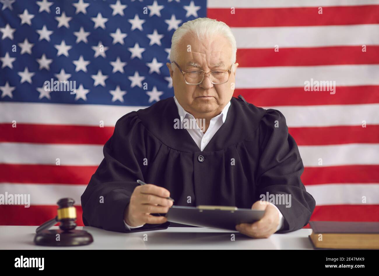 Senior man professional judge signing verdict papers over american flag Stock Photo