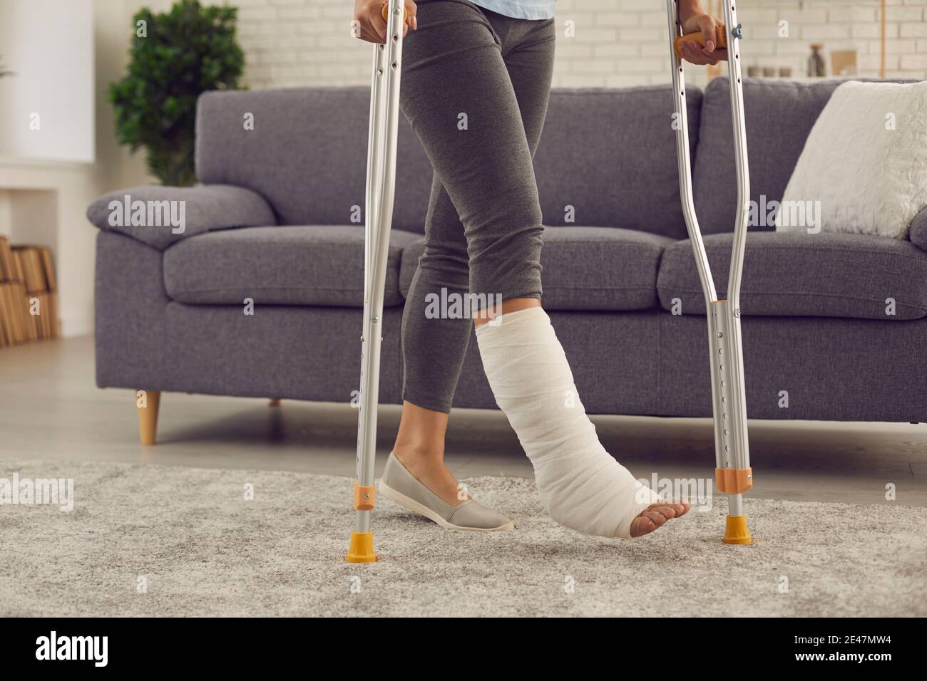 Patient with broken leg in plaster cast undergoes rehabilitation and walks with crutches Stock Photo