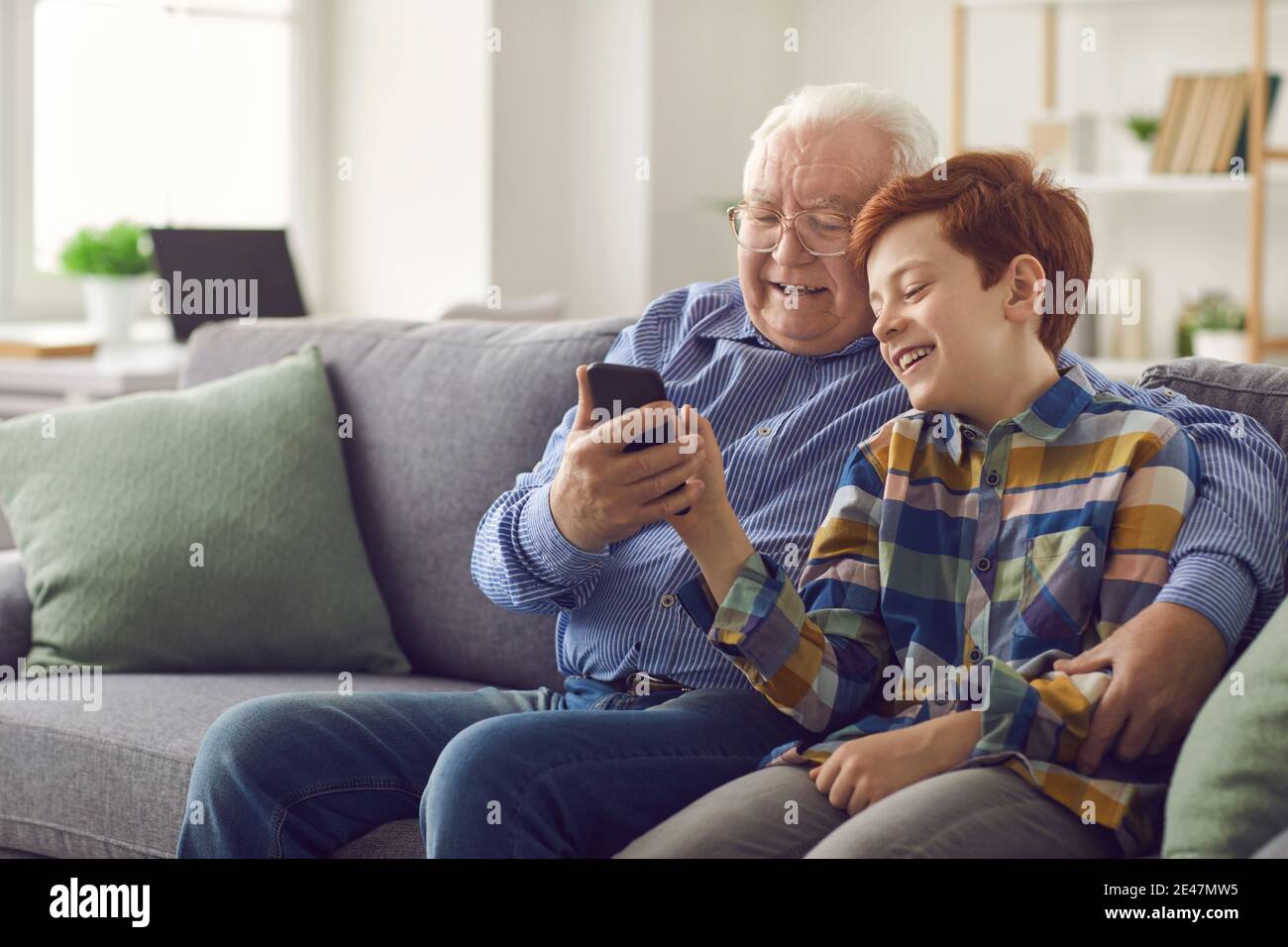 Grandson showing grandpa how to use social media or make video call on mobile phone Stock Photo