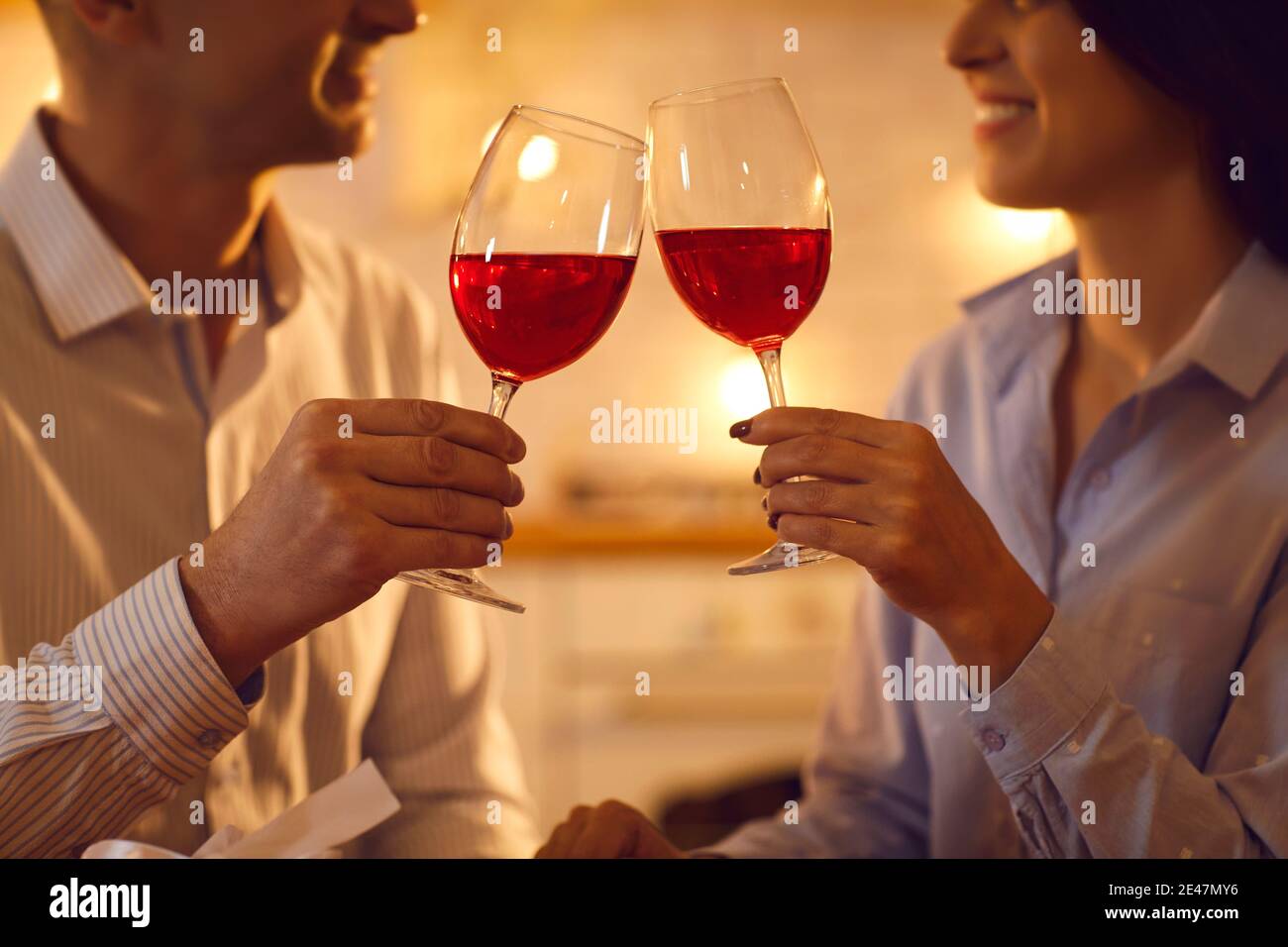 Man and woman in love enjoying red wine and clinking glasses on romantic evening at home Stock Photo