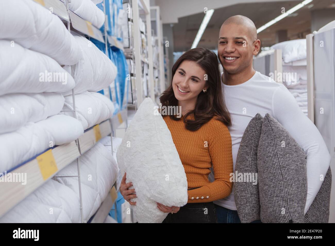 Lovely multiracial couple buying new pillows at home goods store. Charming woman shopping for bedding with her handsome boyfriend Stock Photo Alamy