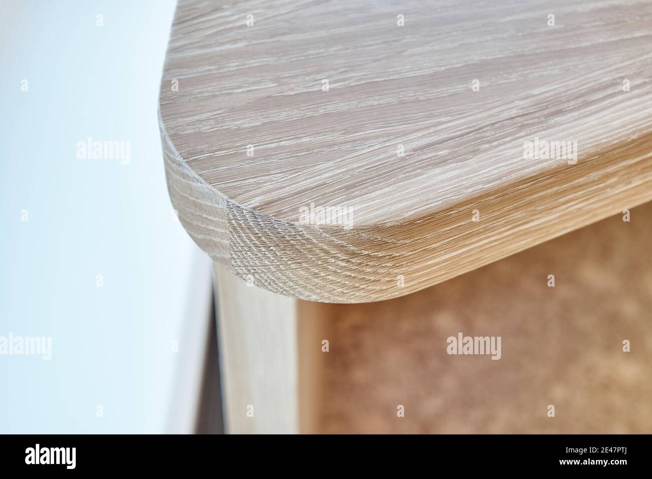 Elegant writing desk made with bleached solid oak timber stands on a cork floor in light room, extreme closeup Stock Photo