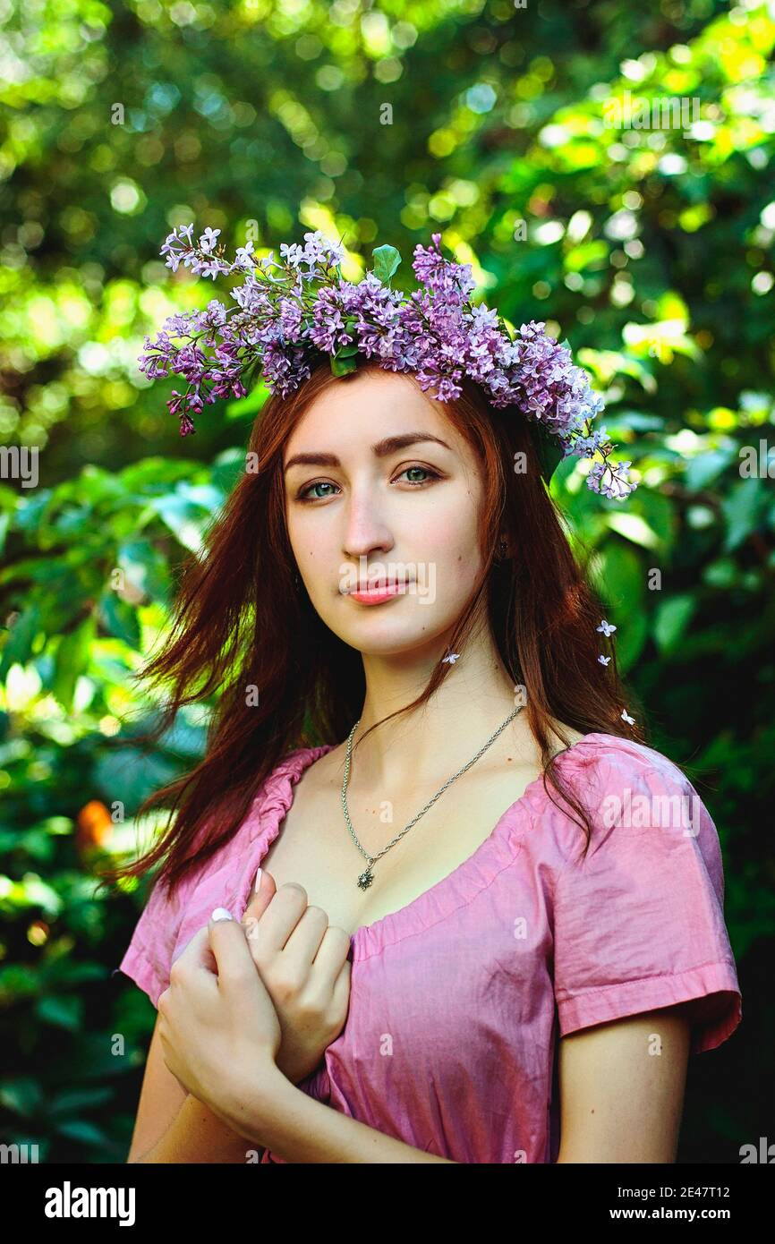 Portrait of young beautiful woman in pink dress in spring garden with ...