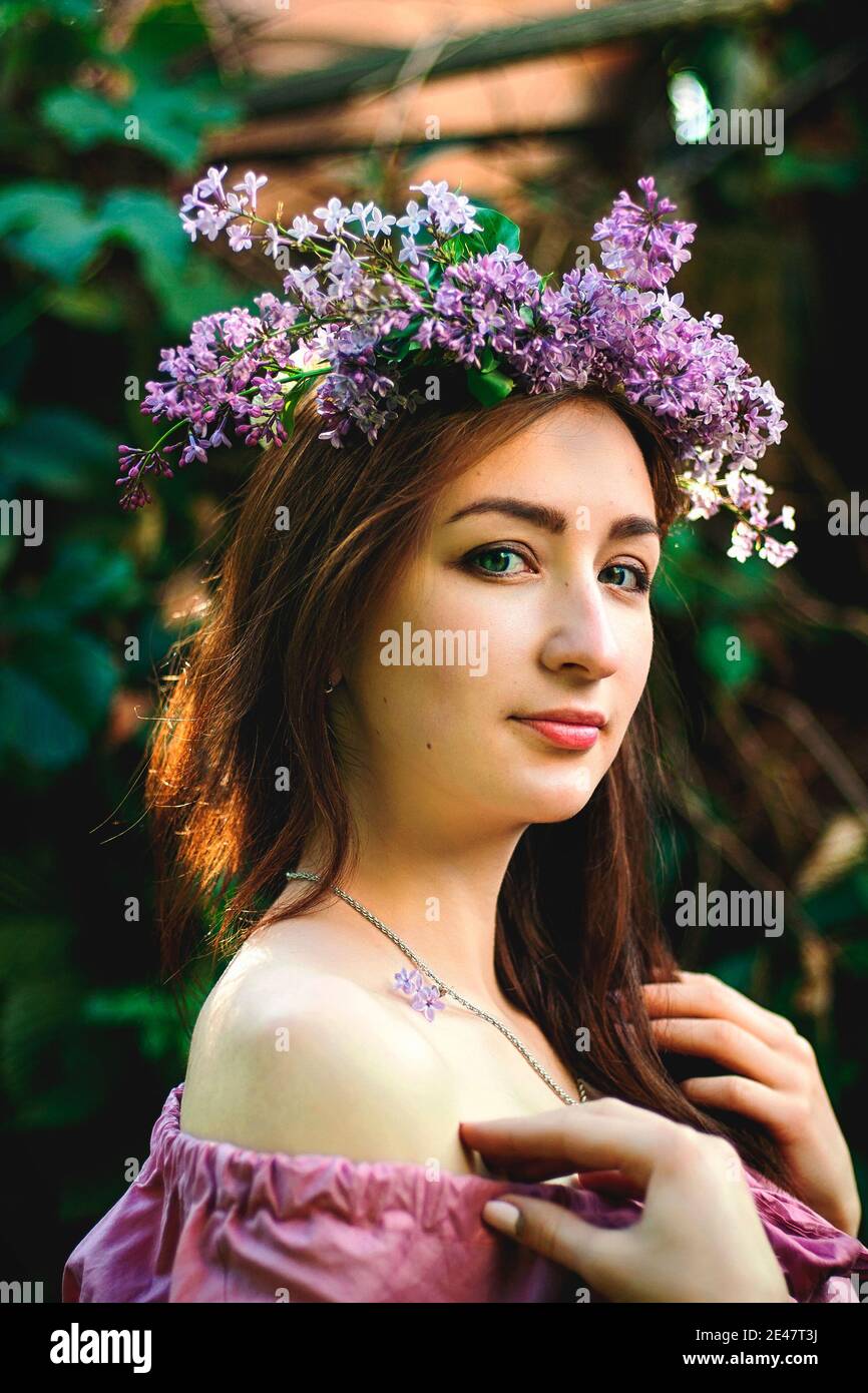 Portrait of young beautiful woman in pink dress in spring garden with ...