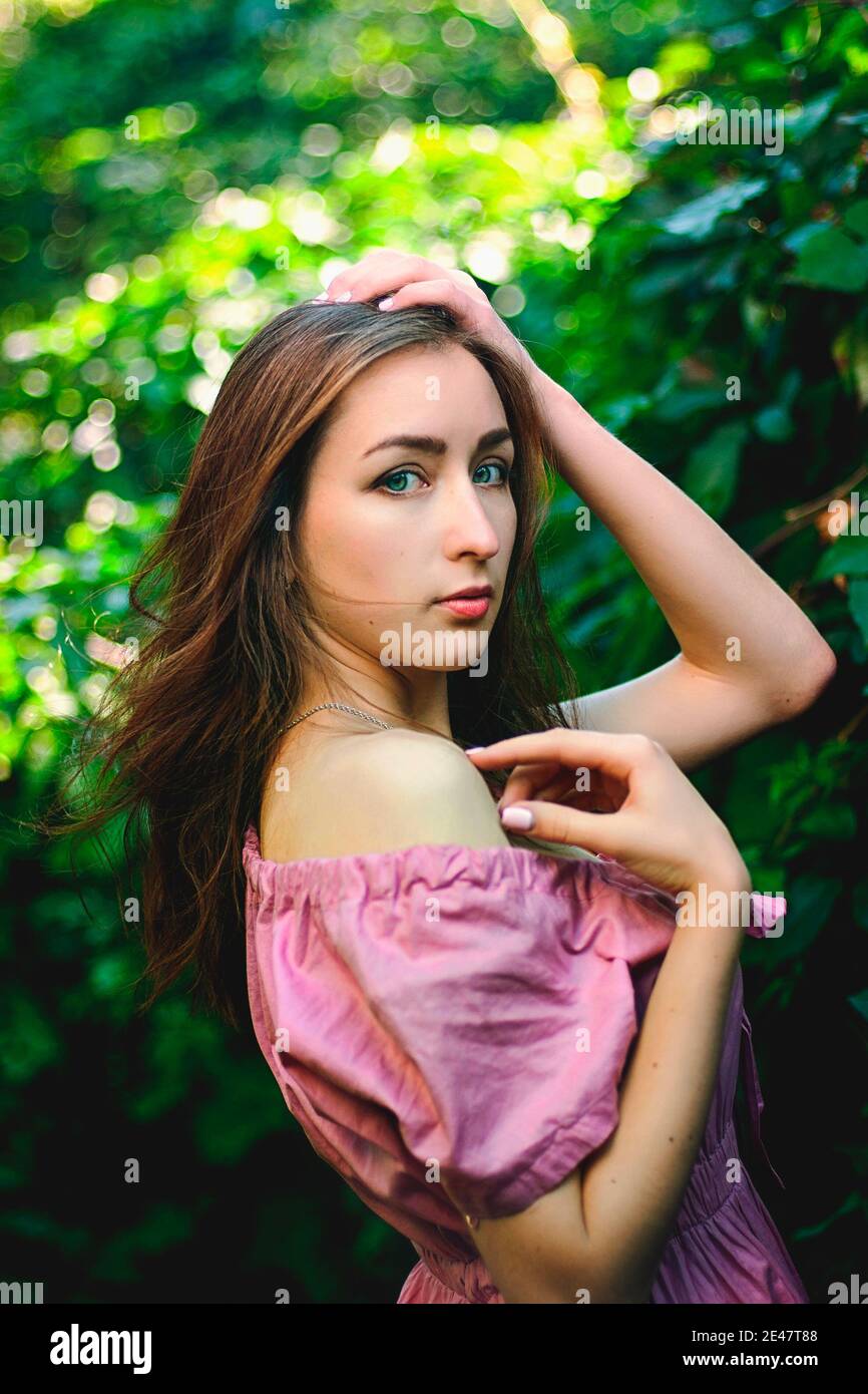 Portrait of young beautiful woman in pink dress in spring garden with ...