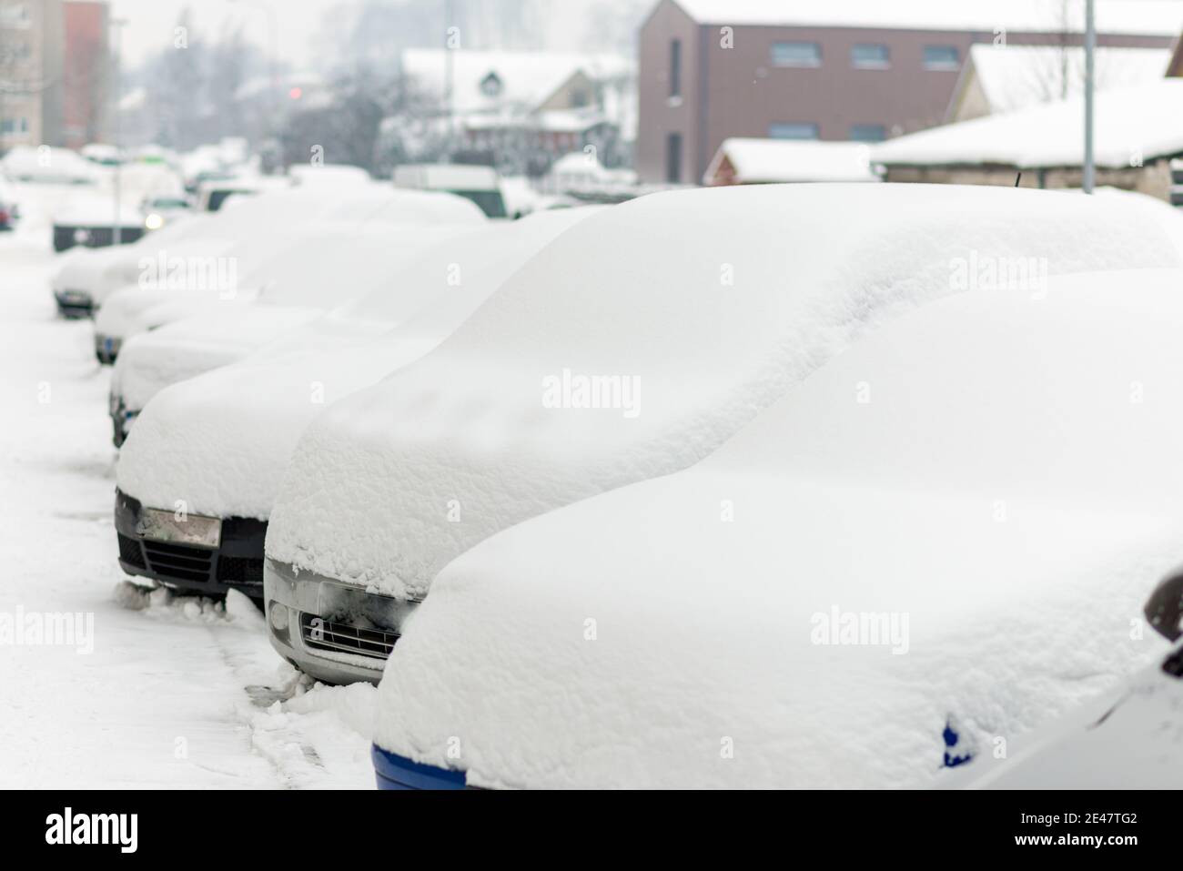 Snow covered cars parked in a row next to each other. Cars on the ...