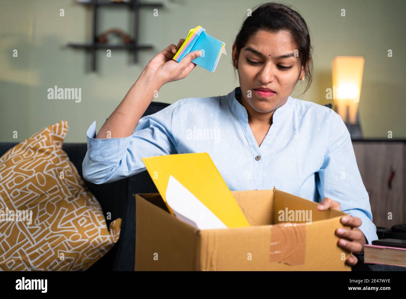 Angry business woman employee throwing sticky notes inside the box due to loss of job, fired, laid off or terminated from company without warning Stock Photo