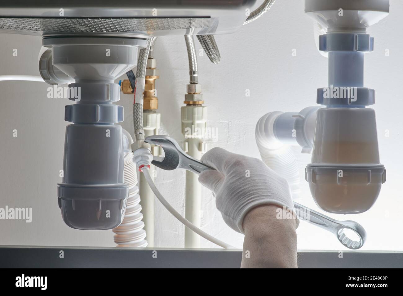 Plumbing work theme. Hand with wrench tighten screw on pipe Stock Photo