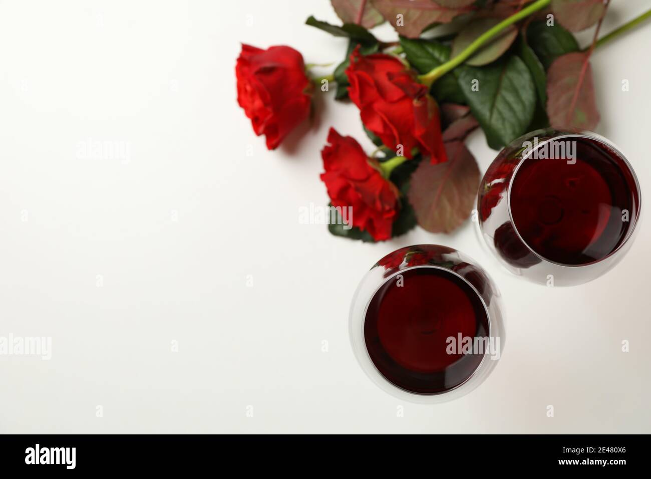 Red roses and glasses of wine on white background, space for text Stock ...