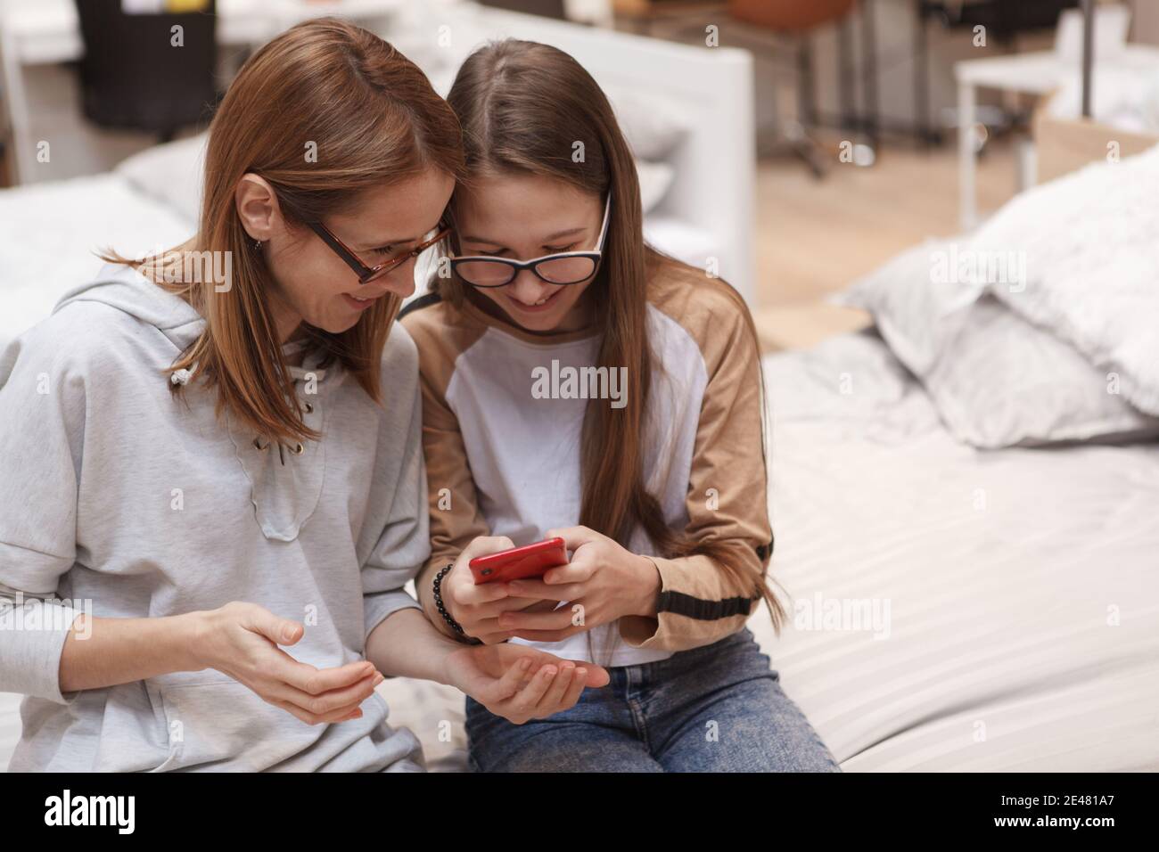 Teenage giel showing something on her smart phone to her mom Stock Photo