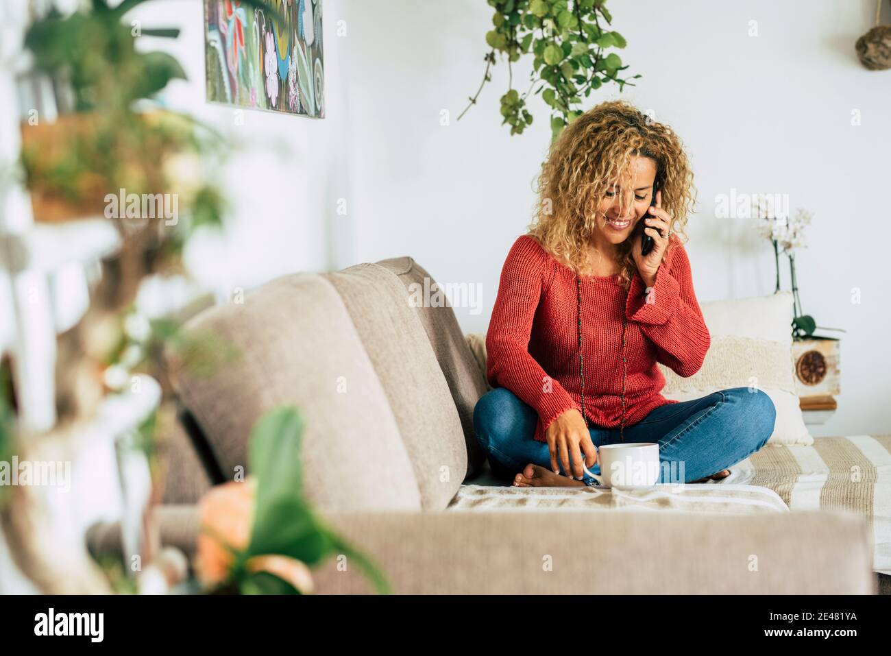 Cheerful and happy beautiful woman at home enjoy a phone call sitting on the sofa - single female people relax in indoor leisure activity alone - happ Stock Photo