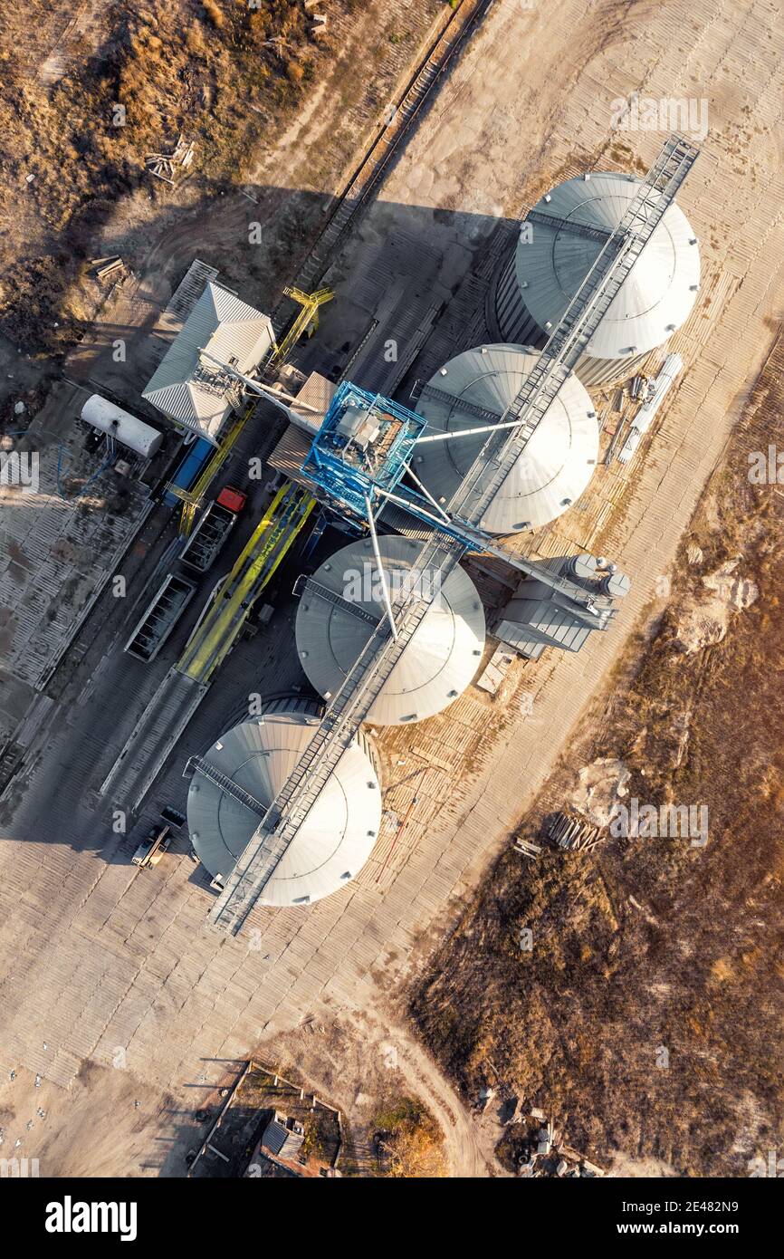Top down view modern steel agricultural grain granary silos cereal storage warehouse loading cargo grain carrier at sunset. Agribuisness farmland Stock Photo