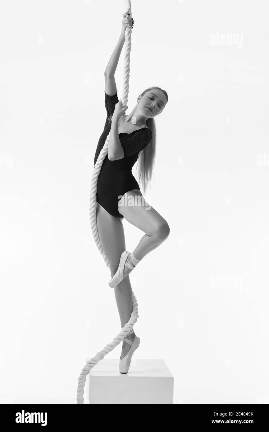 graceful ballerina in pointe shoes is posing with rope on white studio background. Black and white photo. Stock Photo