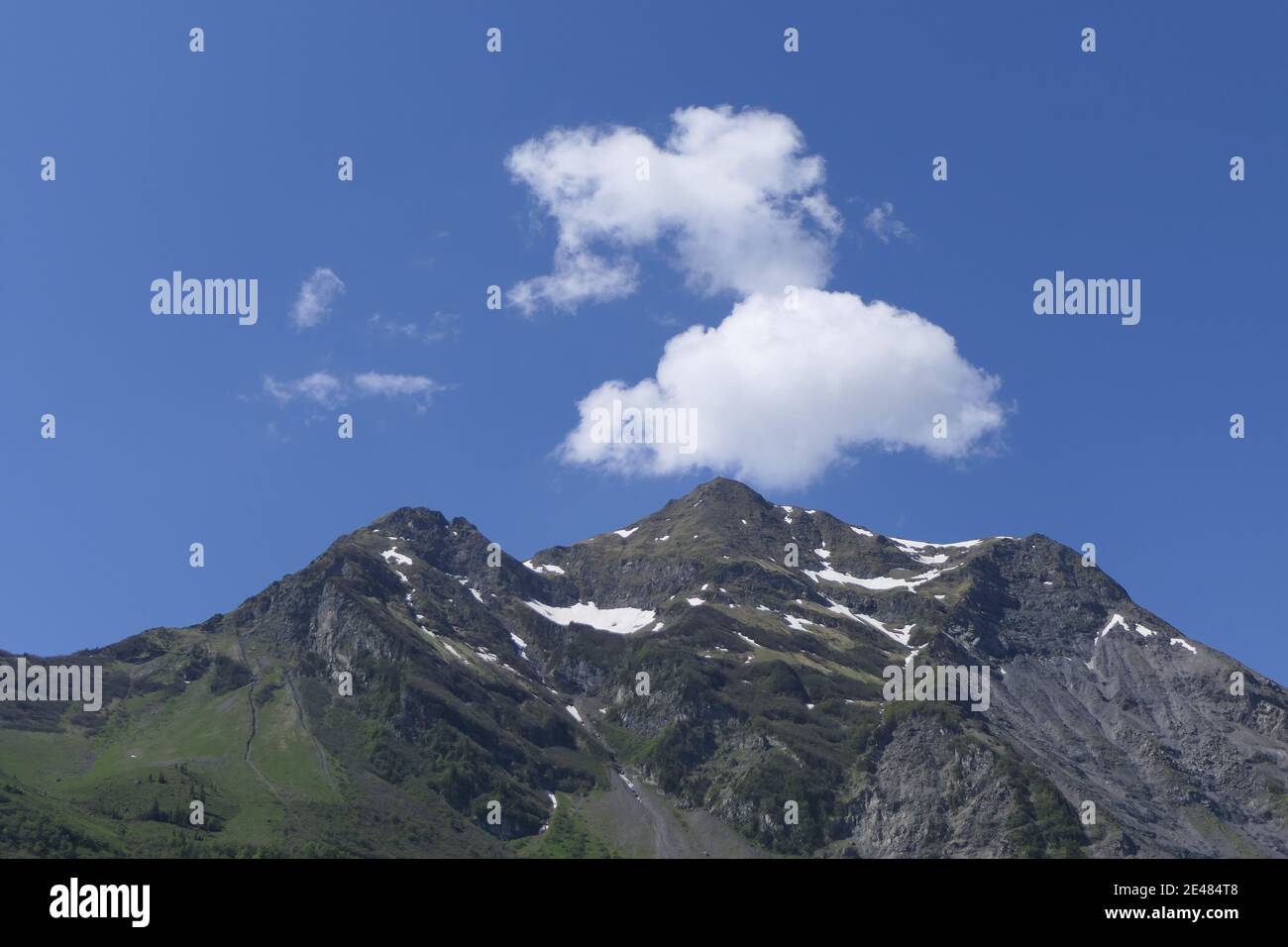 Mountain top in clear sky with snow and clouds that look like smoke