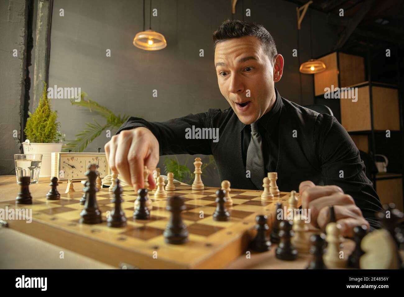 Caucasian man chess player sitting at home and playing chess alone
