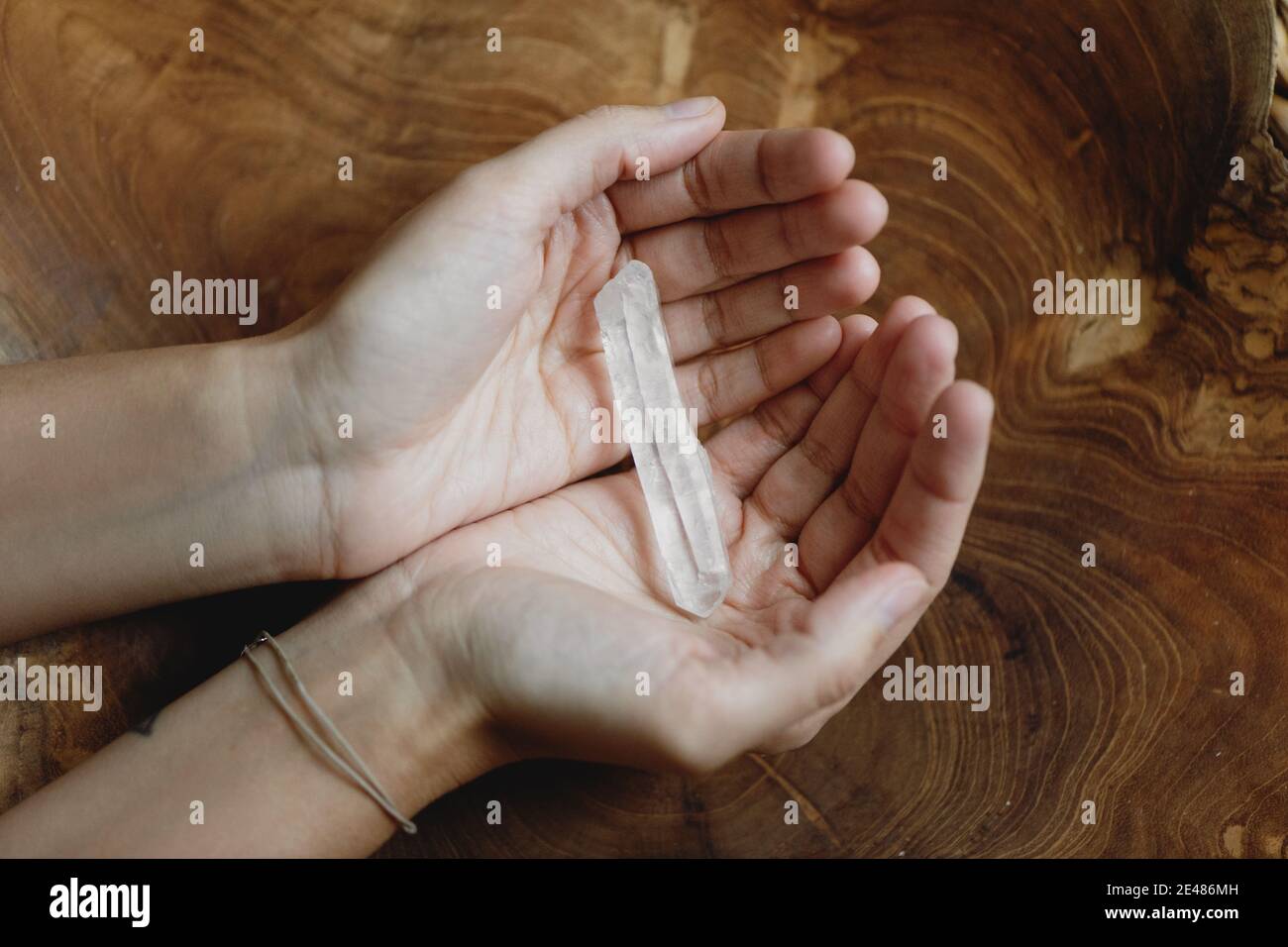 Woman's hands holding energy healing crystal. Top view. Stock Photo